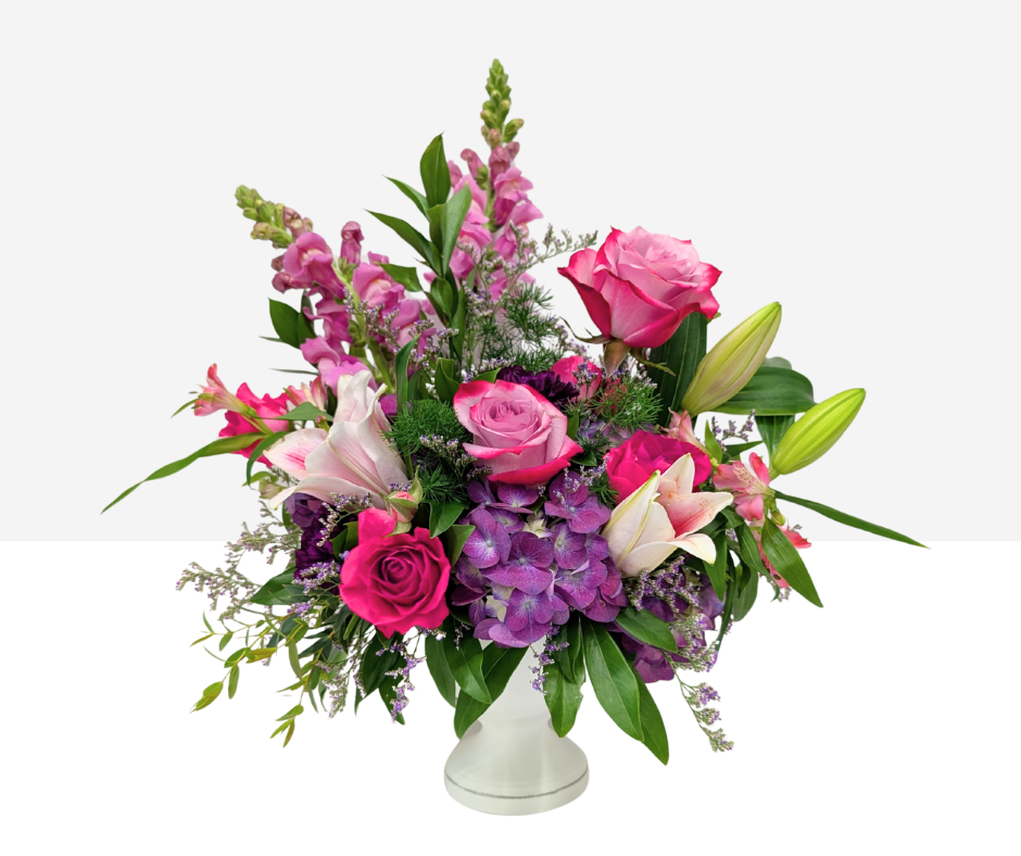 Floral arrangement with pink and purple flowers in a white vase on a white background