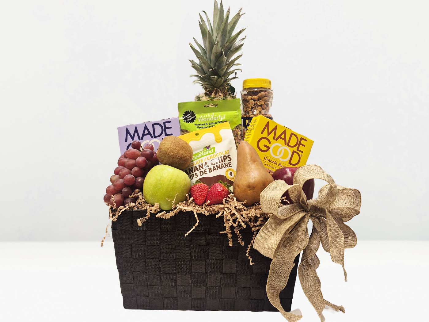 Fruit basket with a variety of fruits and snacks on a white background