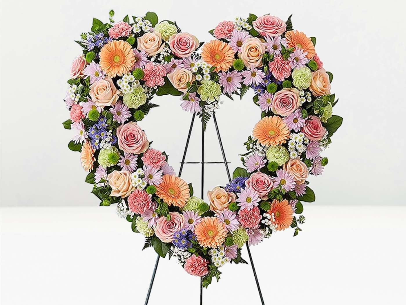 Heart-shaped floral arrangement on a stand against a white background